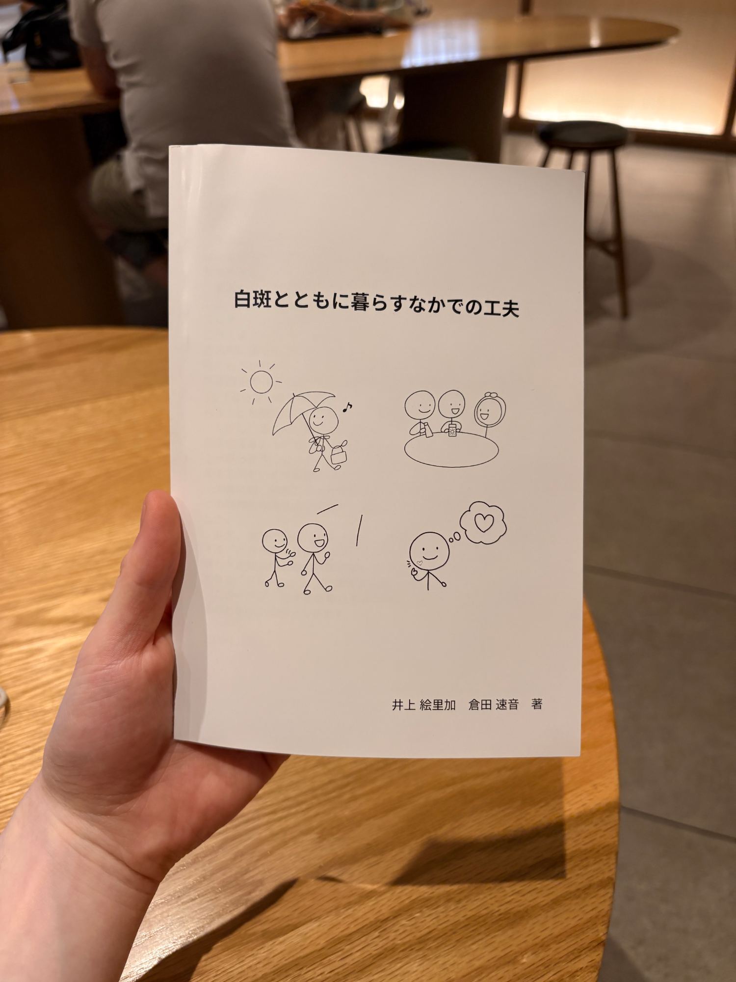 冊子「白斑とともに暮らすなかでの工夫」を手に持っているところ